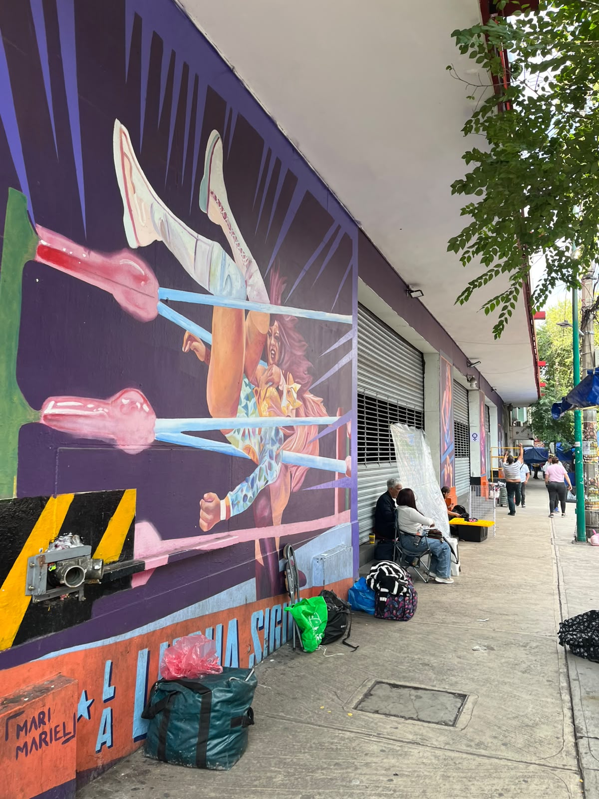 Mural de una luchadora pintado en la calle, junto a la Arena México