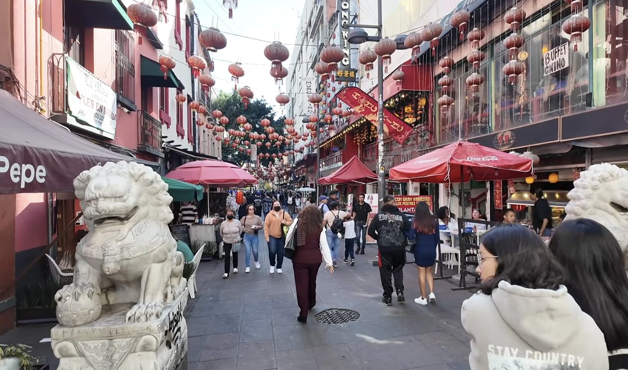 Calle Dolores del Barrio Chino de la CDMX decorada con farolillos rojos, leones guardianes de piedra y terrazas de restaurantes.