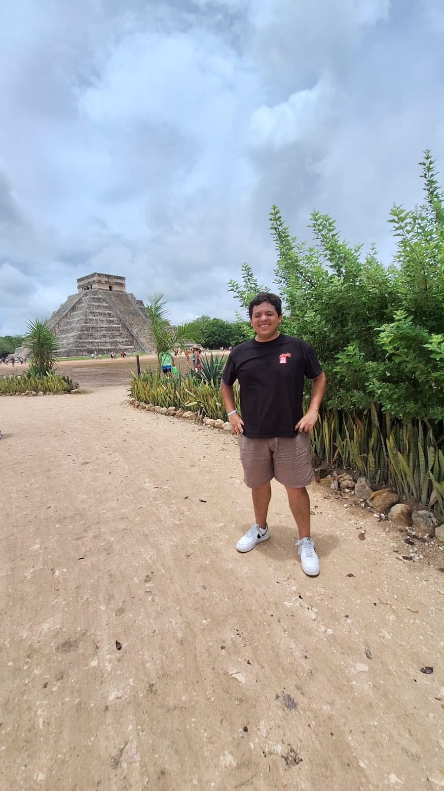 Camino de acceso a Chichén Itzá rodeado de vegetación con la pirámide al fondo