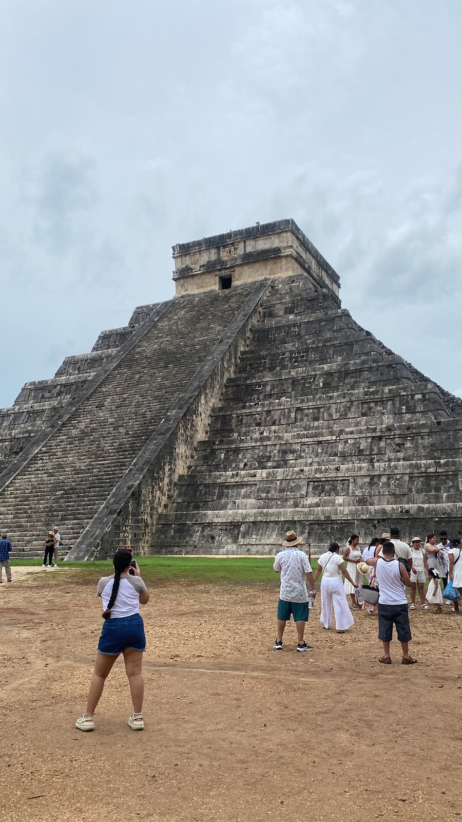 Grupos de turistas frente a la pirámide de Chichén Itzá tomando fotos
