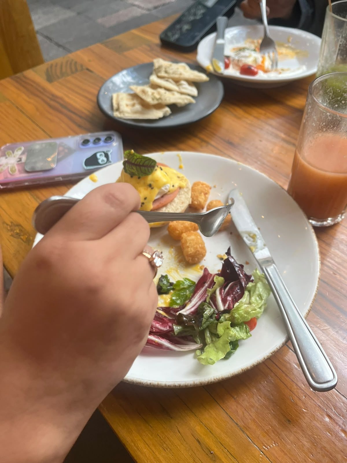 Desayunando en Frëims, plato con huevo benedictino y jugo natural de fondo