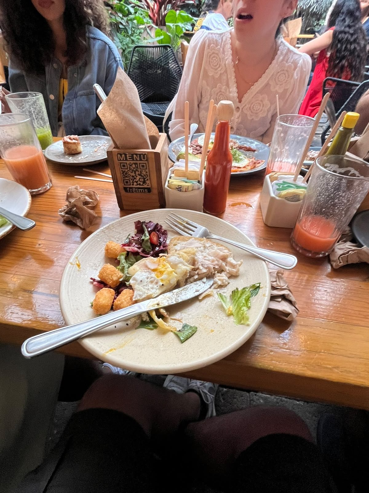 Croque madame de Frëims con huevo, ensalada y papas tater tot sobre la mesa
