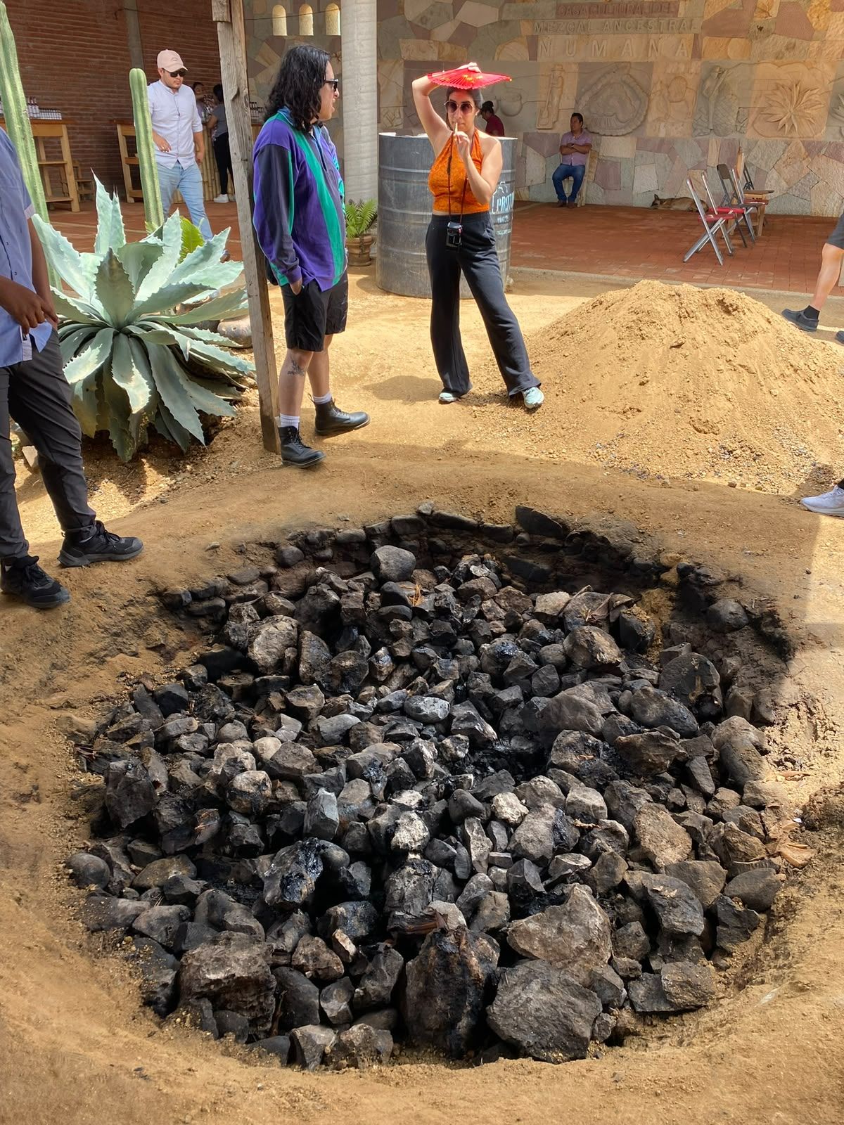 Piñas de agave asándose en el horno de tierra de un palenque de mezcal en Oaxaca