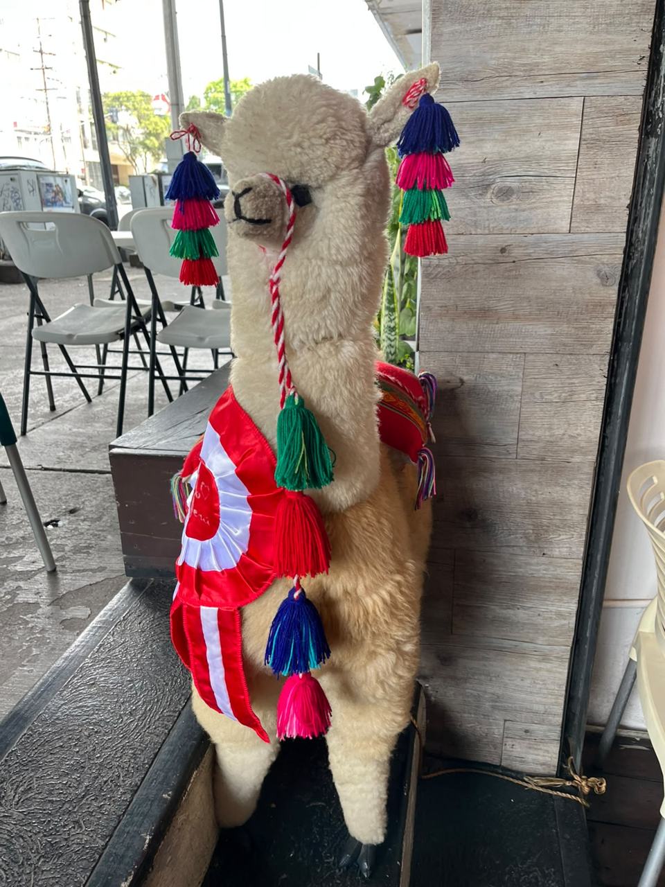 Alpaca decorativa con cintas de la bandera del Perú en la entrada de Pachamama, Narvarte, CDMX