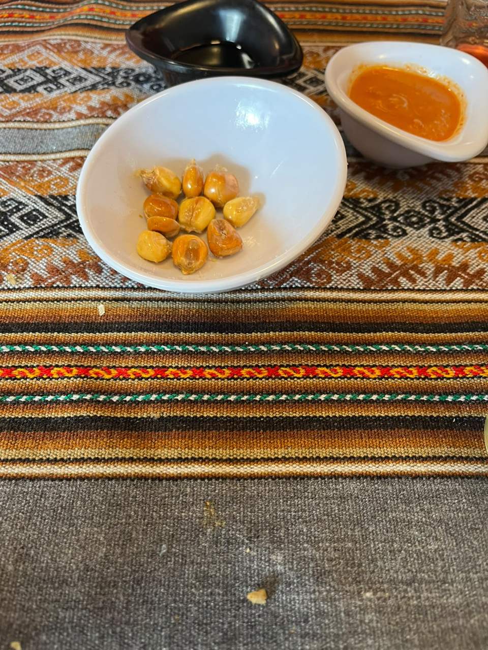 Bol de canchita (maíz tostado) con salsa de ají sobre mantel andino en Pachamama
