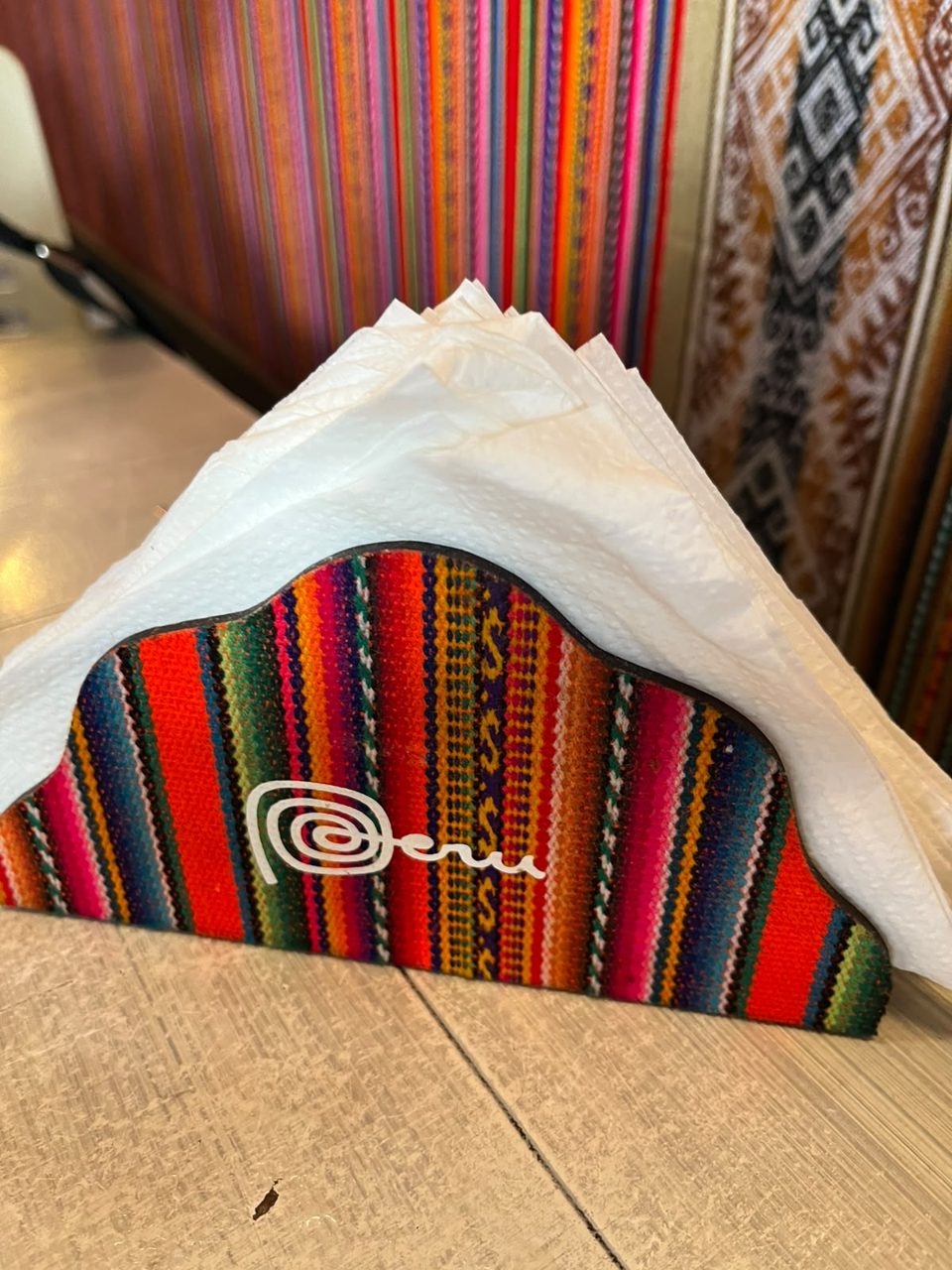 Servilletero con textil andino y el logotipo Perú en una mesa de Pachamama