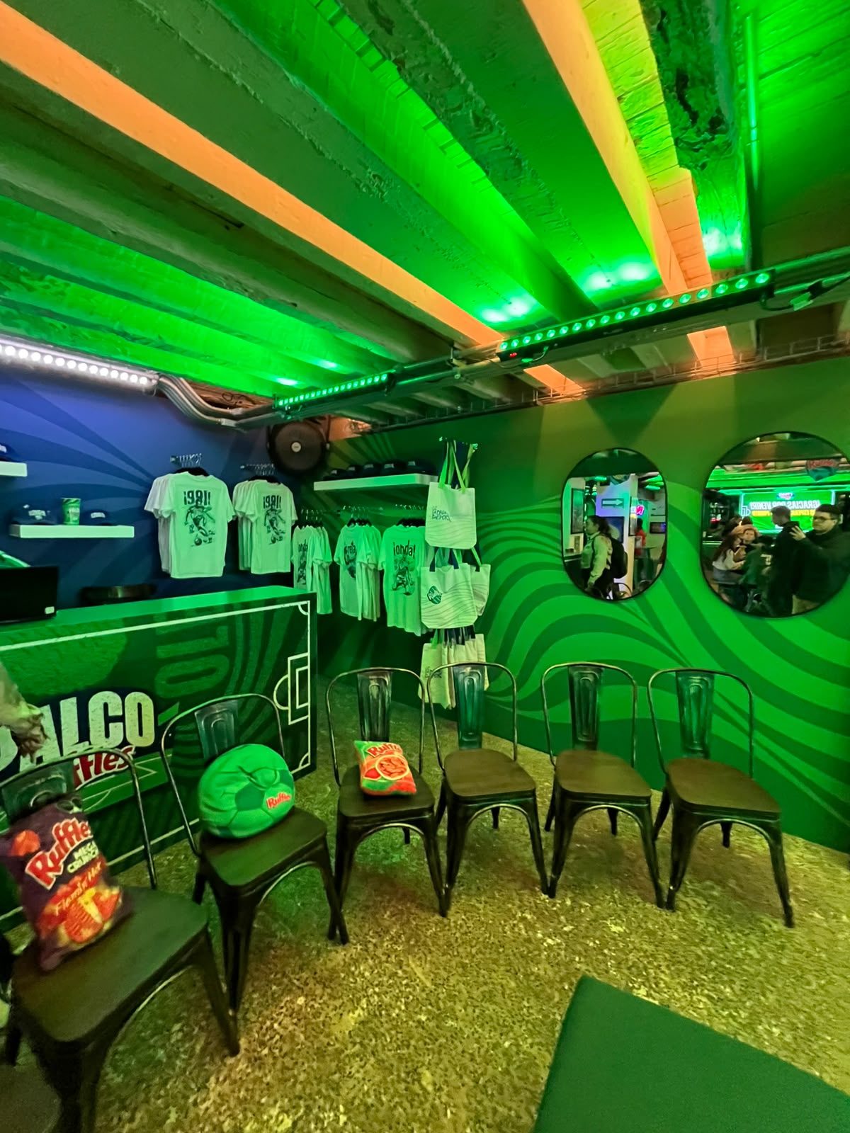 Zona de merchandising del Palco Ruffles con playeras conmemorativas y bolsas tote temáticas a la venta.