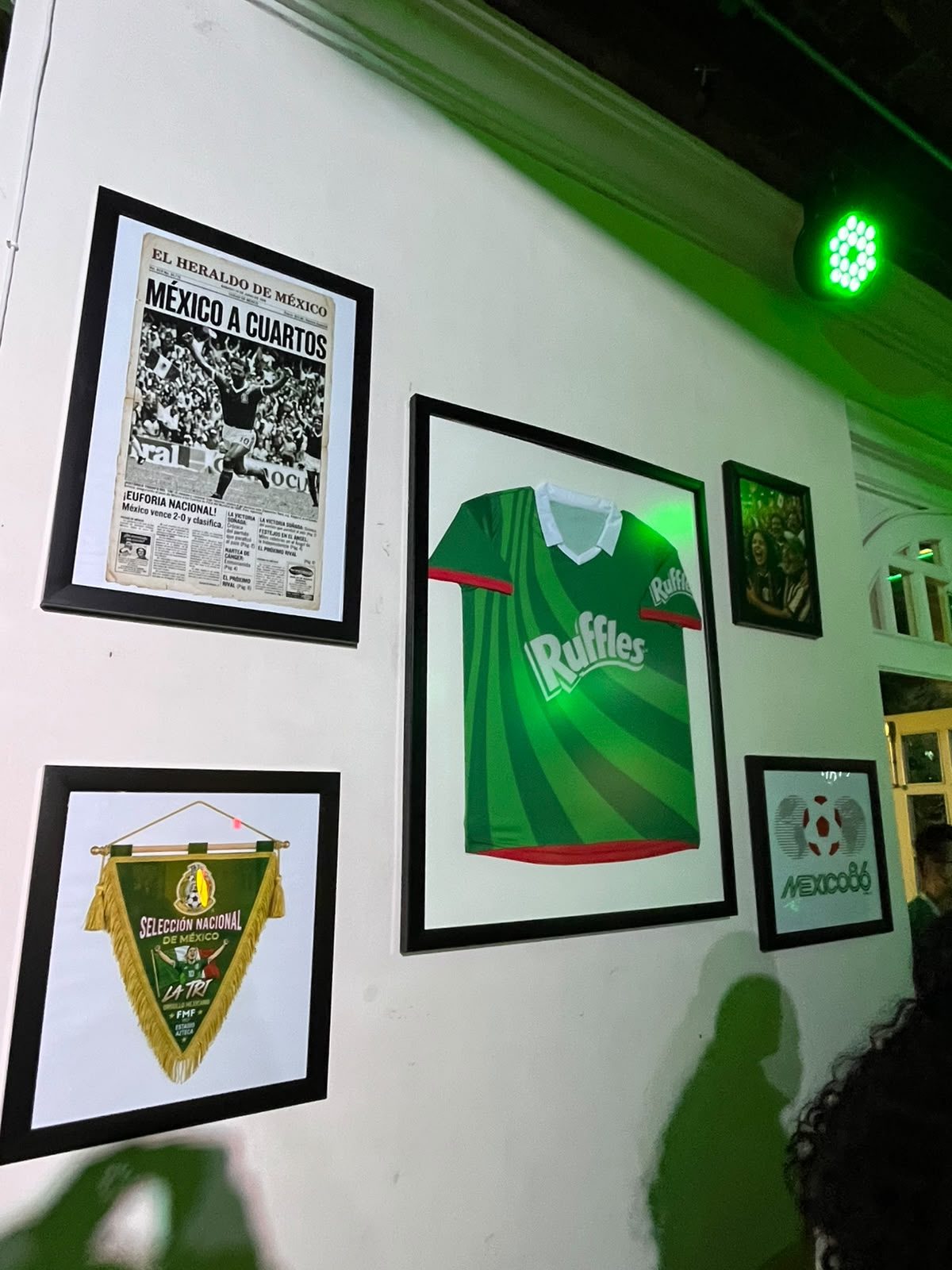 Muro de memorabilia del futbol mexicano en el Palco Ruffles con un jersey verde de Ruffles enmarcado.