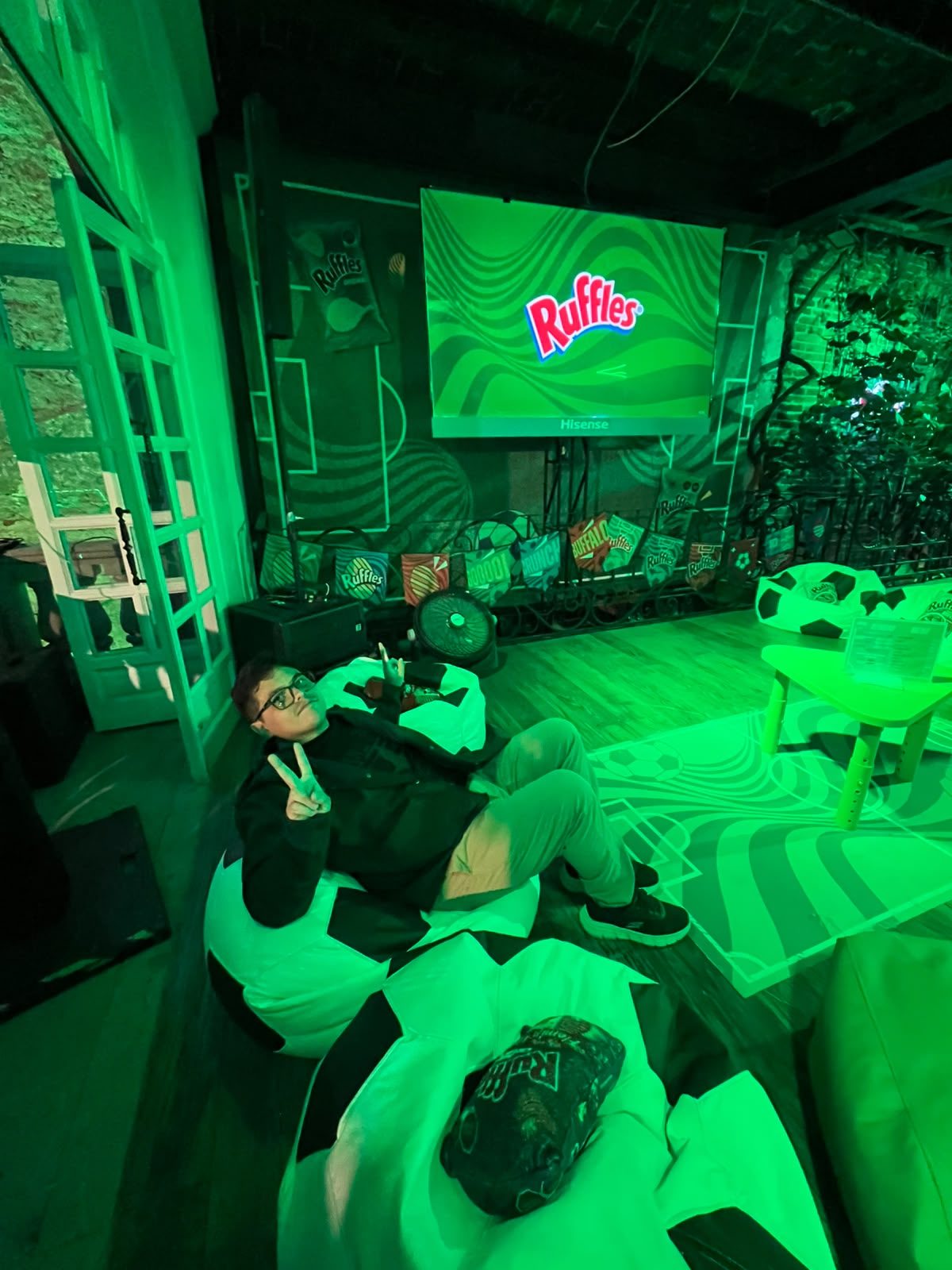 Zona de descanso del Palco Ruffles con puffs en forma de balón frente a la pantalla y un exhibidor con sabores de Ruffles.