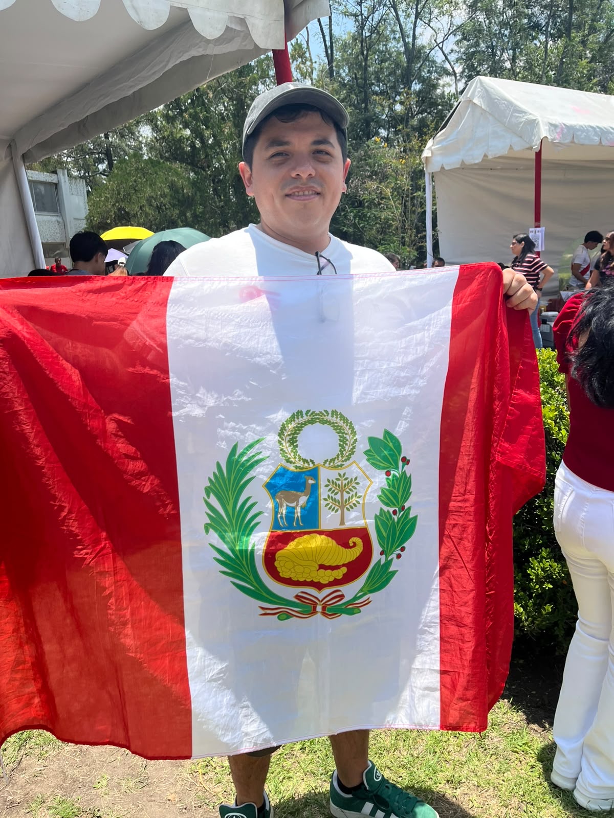 Hombre sosteniendo la bandera de Perú en la celebración de la Independencia en el Parque del Perú, Ciudad de México