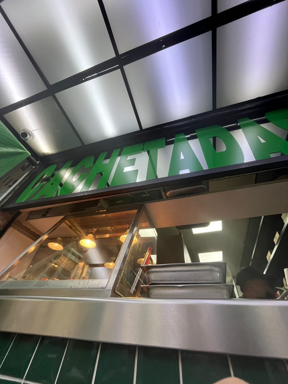Letrero verde con la palabra CACHETADAS sobre la barra de Tacos Atarantados, Roma Norte