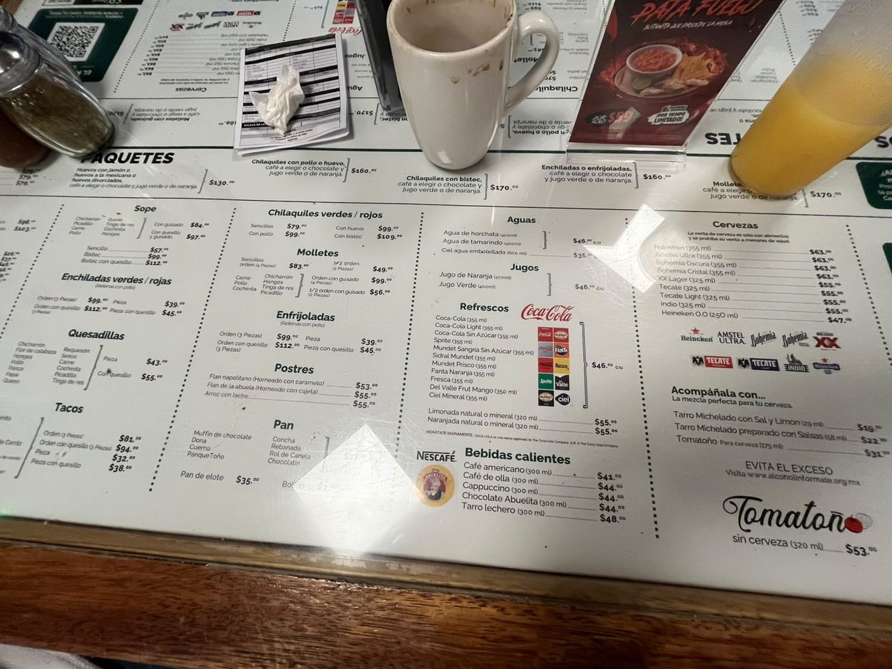 Carta de La Casa de Toño bajo el cristal de la mesa con precios de paquetes, enfrijoladas, jugos y bebidas calientes
