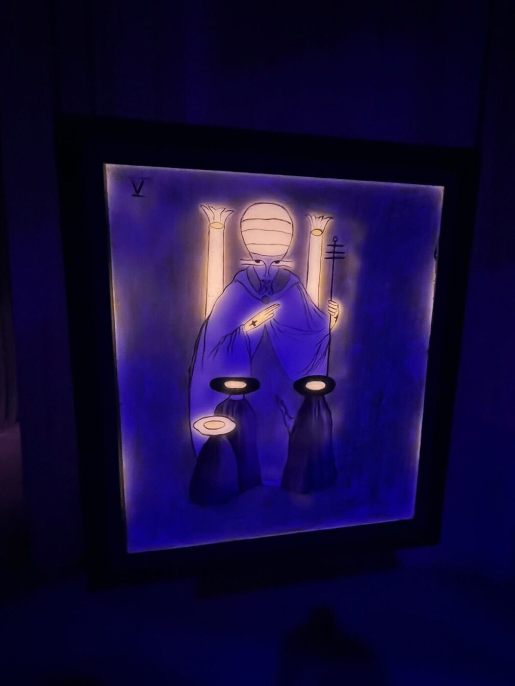 Carta V del tarot de Leonora Carrington, El Hierofante, iluminada con luz ultravioleta azul en la exposición Laberinto Mágico