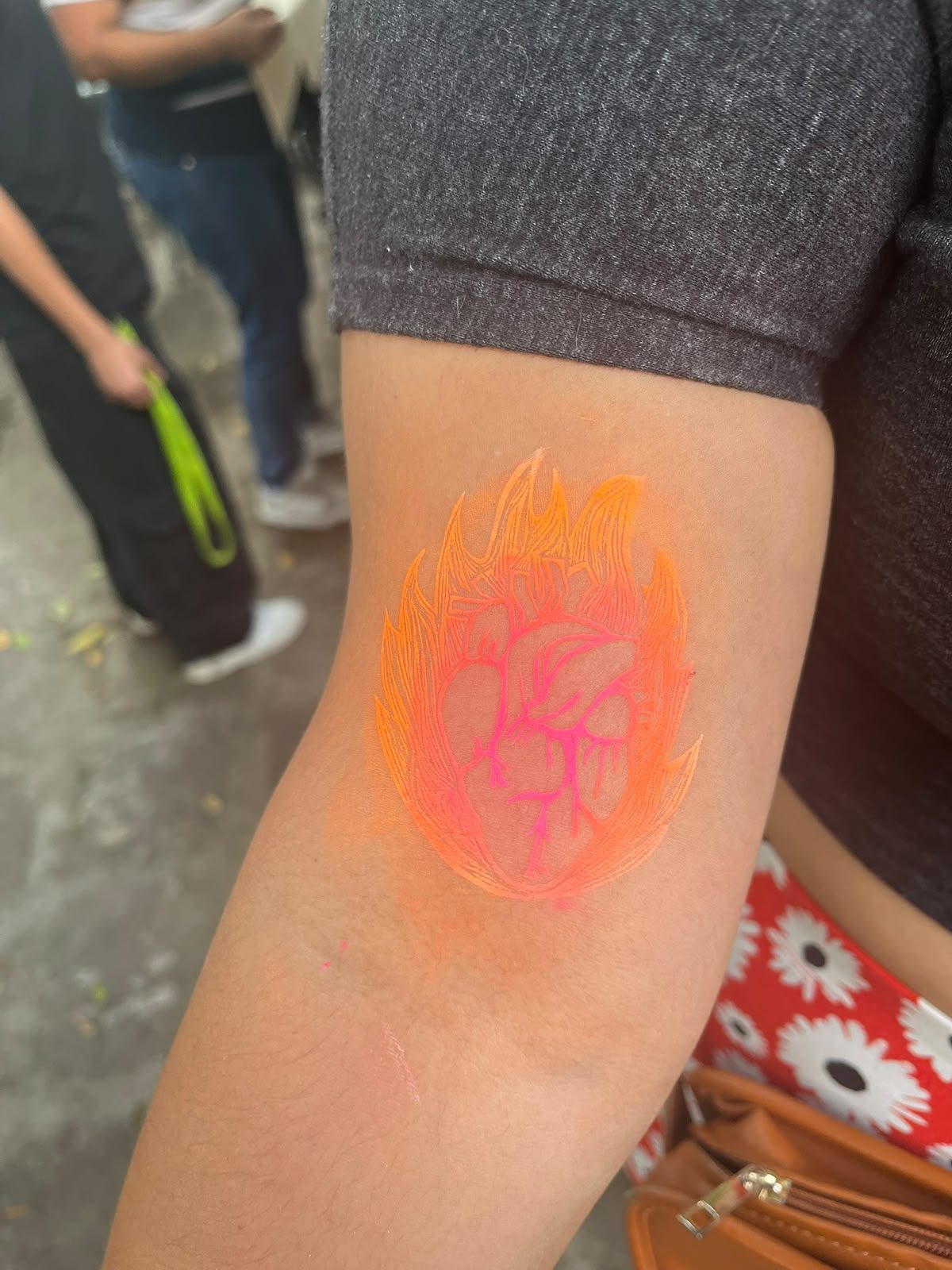 Grabado temporal de un corazón anatómico en llamas estampado en tinta naranja sobre un brazo, del taller de estampa del Munae