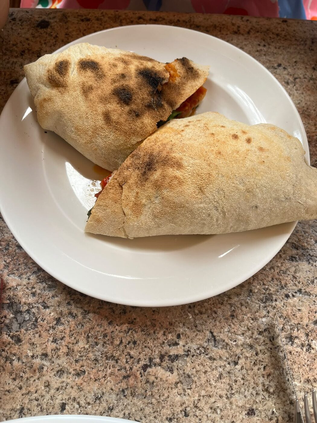 Calzone de ricotta, albahaca, mozzarella y roast beef partido a la mitad en un plato blanco en Terraza Margot