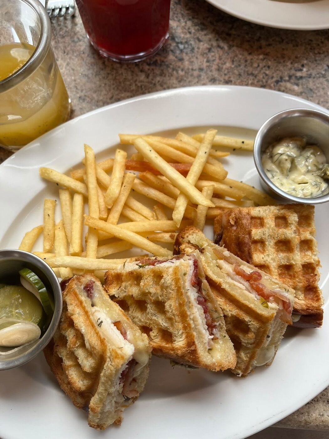 Croque Margot partido en cuatro porciones con papas a la francesa, mayonesa tártara y pepinillos en Terraza Margot, Roma Norte