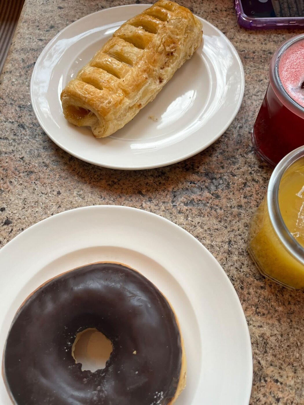 Dona de chocolate y hojaldre de piña en platos blancos junto a dos jugos en frascos de vidrio en Terraza Margot