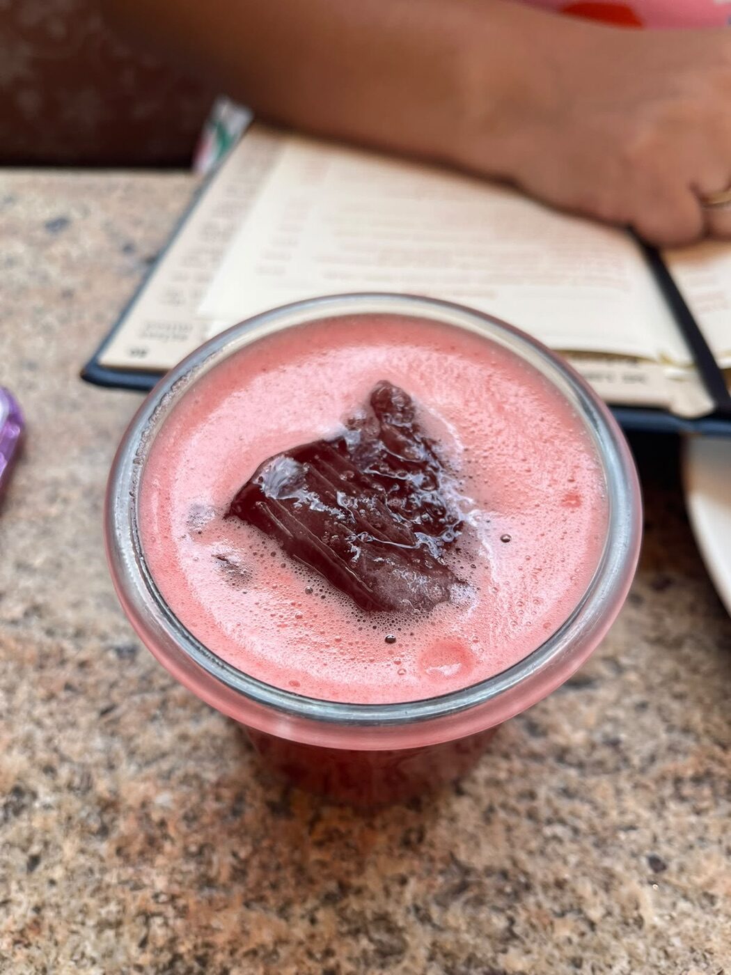 Jugo rojo servido en un frasco de vidrio pequeño sobre la mesa de granito de Terraza Margot