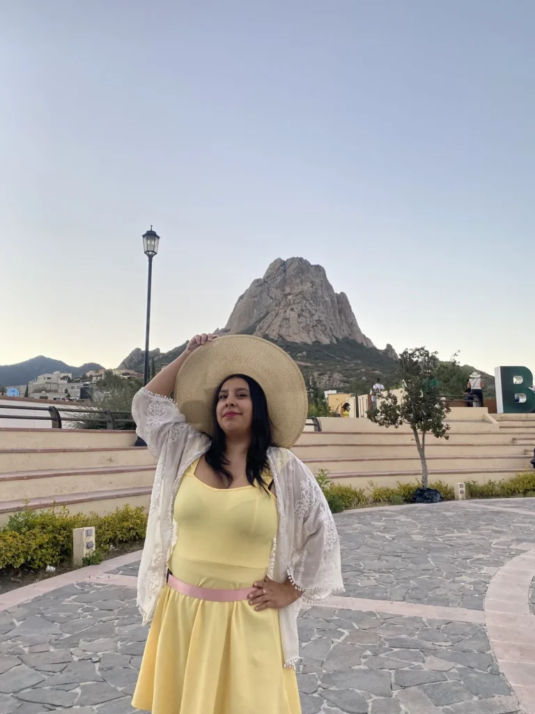 Mujer con sombrero y vestido amarillo en la explanada de Bernal, con la Peña de Bernal al fondo