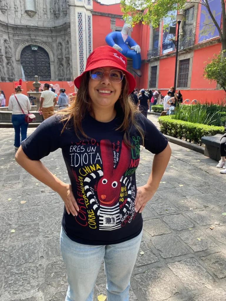 Plaza de la Santa Veracruz con la fachada de piedra de la iglesia y un edificio rojo con una figura inflable gigante, julio de 2024