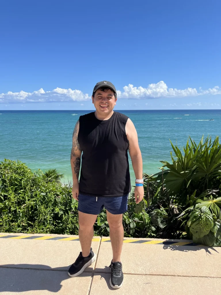 Hombre de pie en un mirador con el mar Caribe turquesa detrás, cerca de las ruinas de Tulum