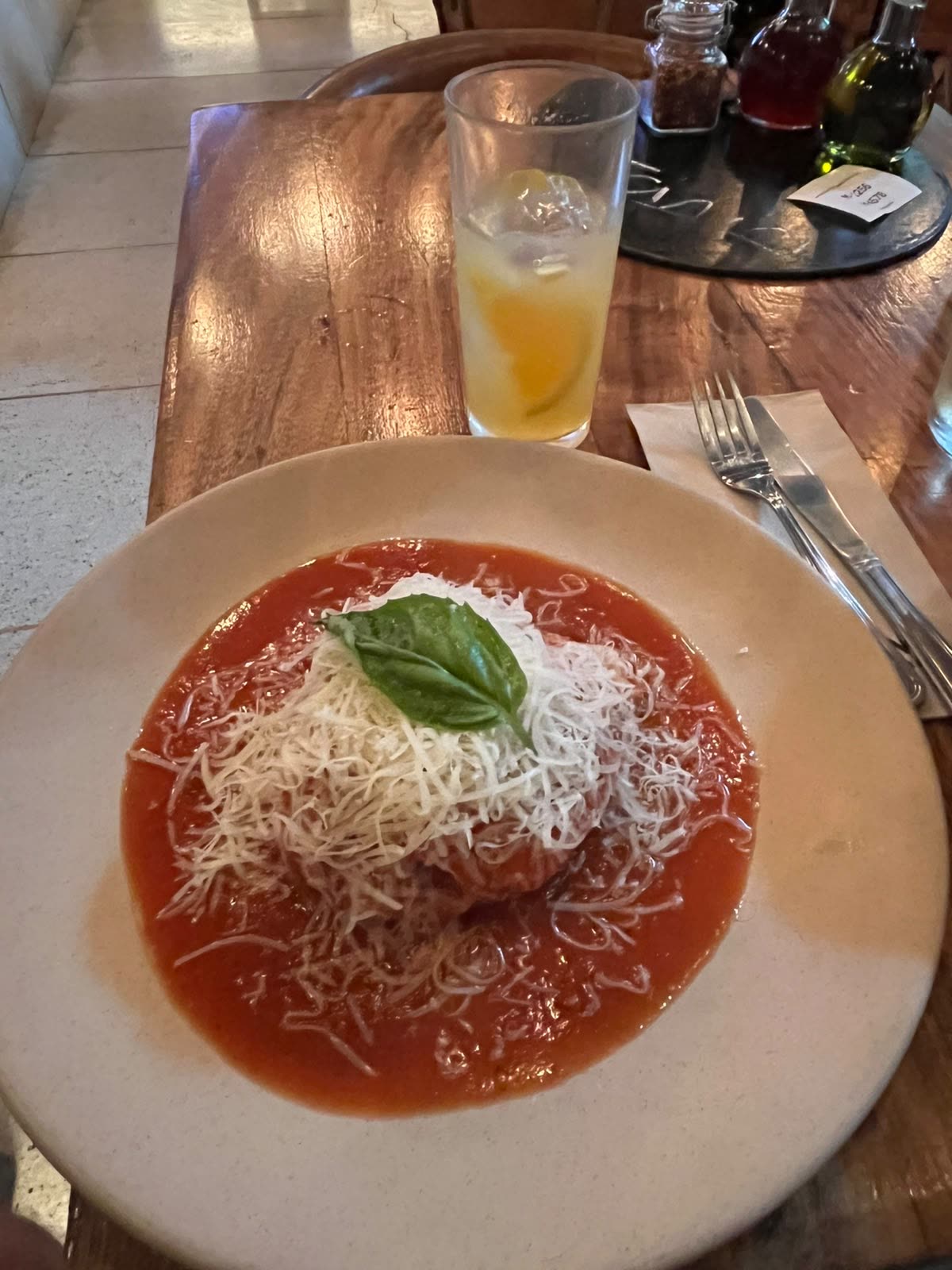 Plato de lasaña bañada en salsa de tomate con parmesano rallado y albahaca en Cancino Centro CDMX